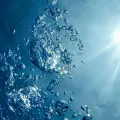 Cette image montre des bulles d’air sous l’eau éclairées par des rayons lumineux pénétrant à travers une surface limpide.